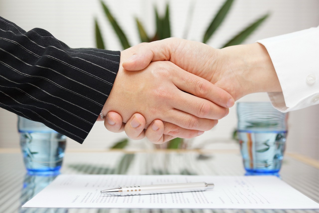 businessman and businesswoman shaking hands over signed contract.